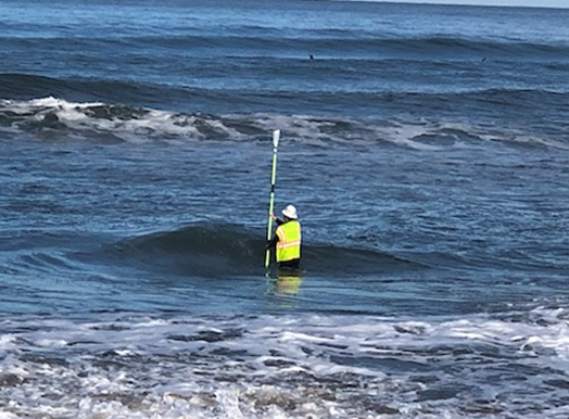Surveying the accuracy of the fill placement which requires the surveyor to get into the tidal surf action.